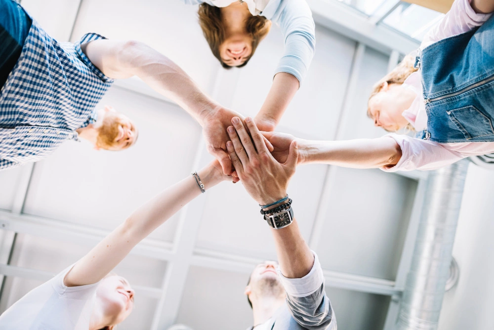 Team beim gemeinsamen Handschlag als Symbol für erfolgreiche Kommunikation